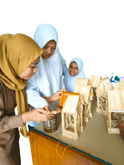 guru perempuan sedang mengajarkan cara pengecatan finishing pada kerajinan stik es krim